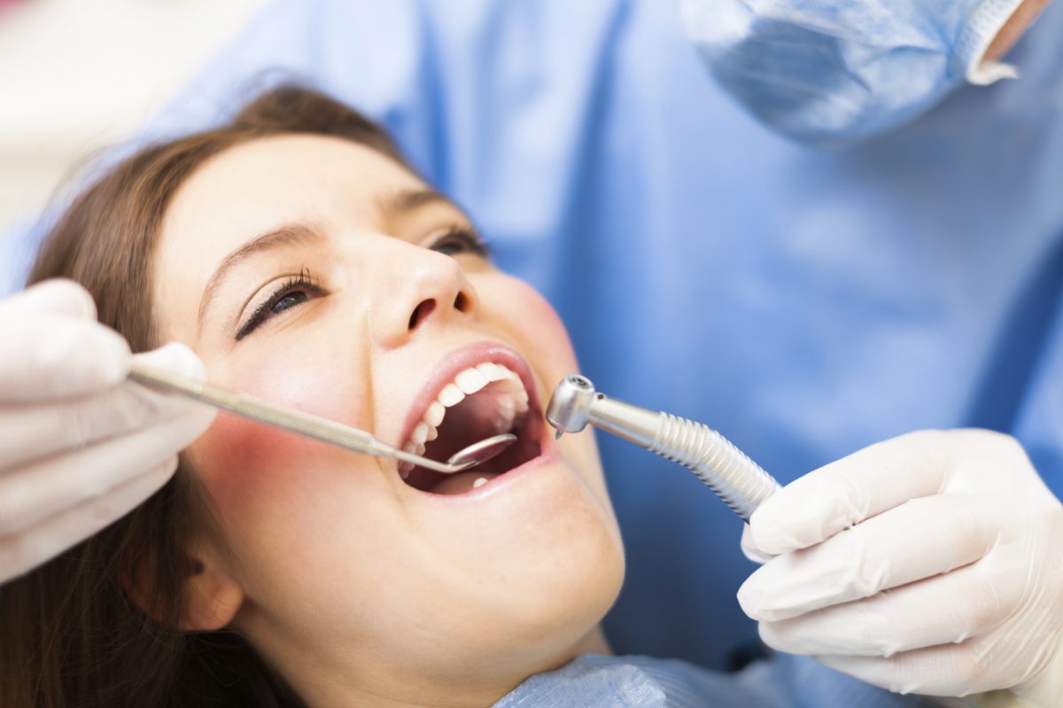 woman in dental chair having teeth looked at